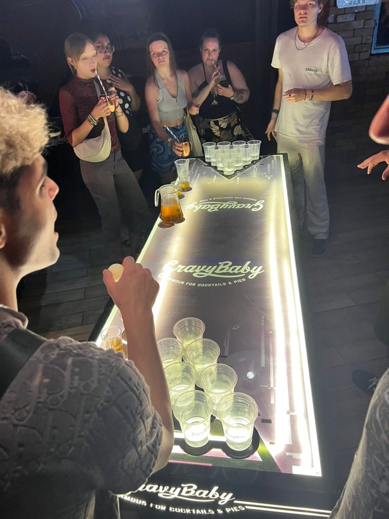 Guests around a lit bar counter on a Travelogue Guesthouse night out