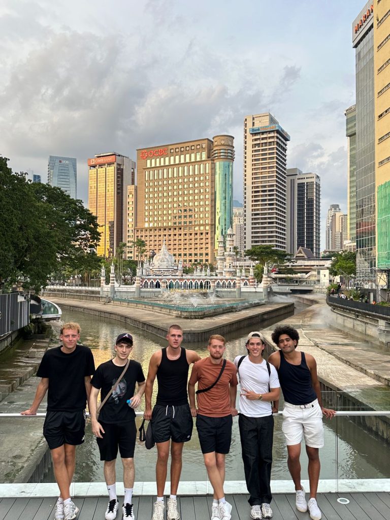 A Travelogue Guesthouse group beside a fountain with the city towers behind them
