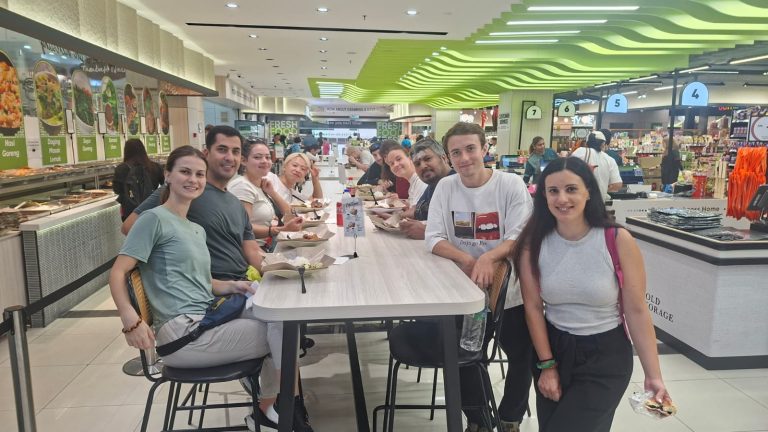 A Travelogue Guesthouse group at a table in a food hall