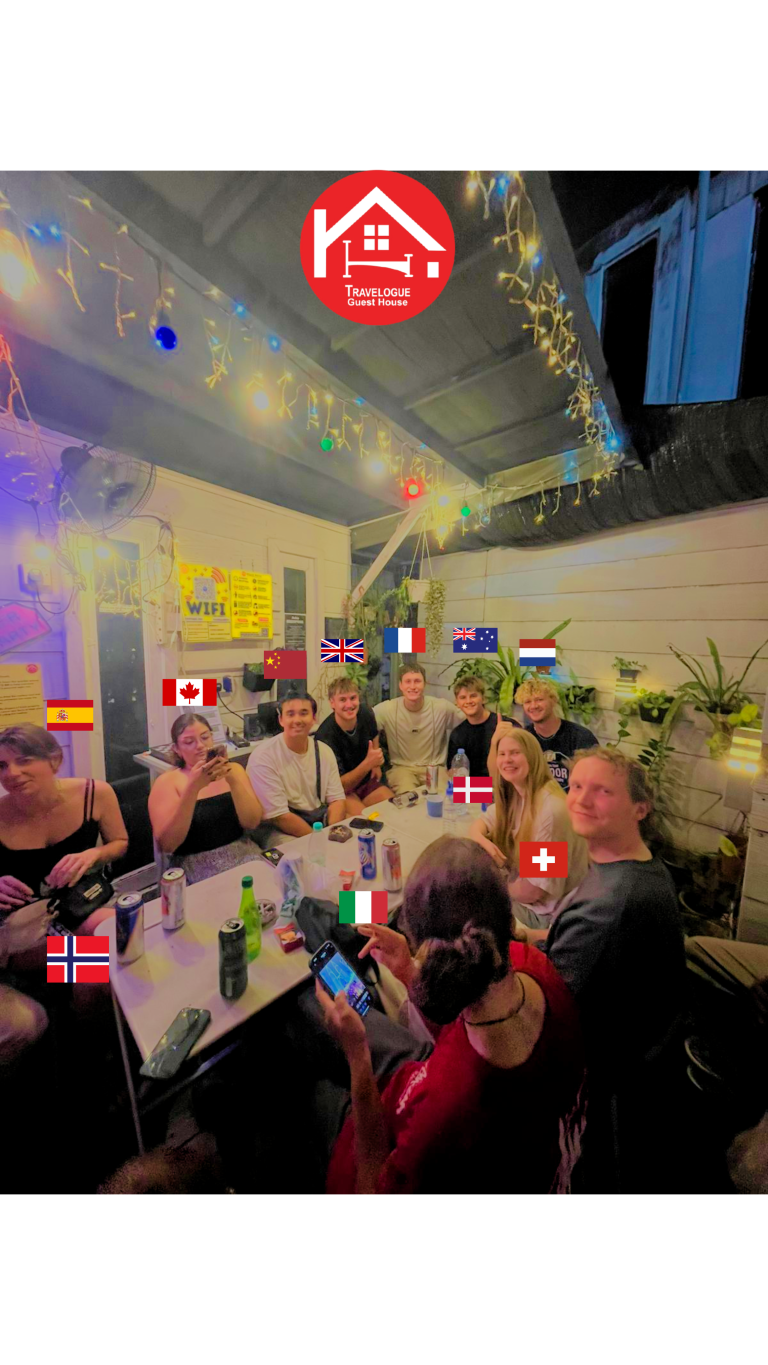 Travelogue Guesthouse guests at a table under the flags hung across the common area
