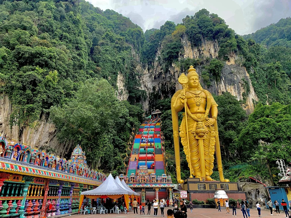 The gold Murugan statue and the 272 rainbow steps below the cave mouth at Batu Caves, Kuala Lumpur