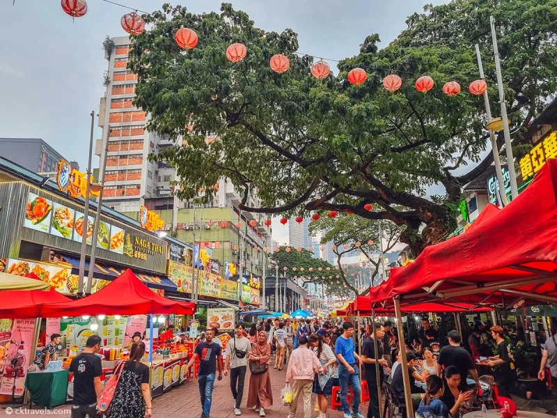 Jalan Alor at night, red lanterns strung the length of the street above the stalls and the tables