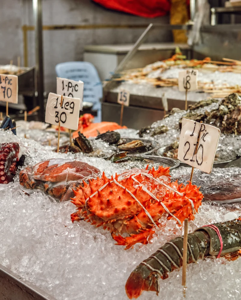 Crab, lobster and prawns on ice with handwritten prices at a Jalan Alor stall