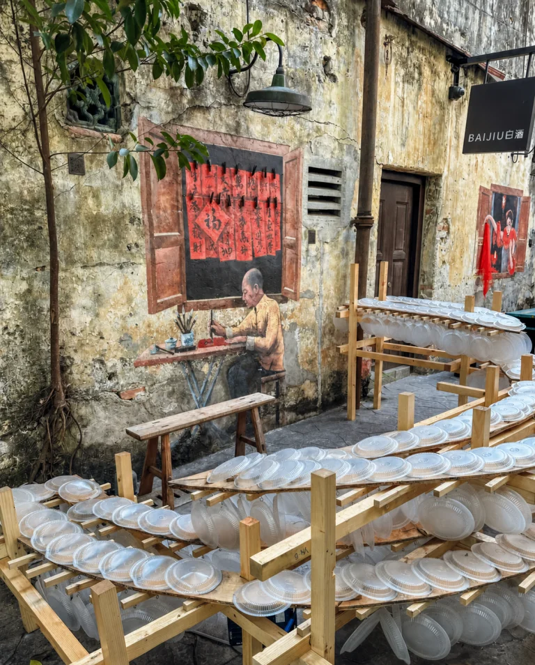 A painted wall and racks of drying bowls in a Kuala Lumpur Chinatown back lane