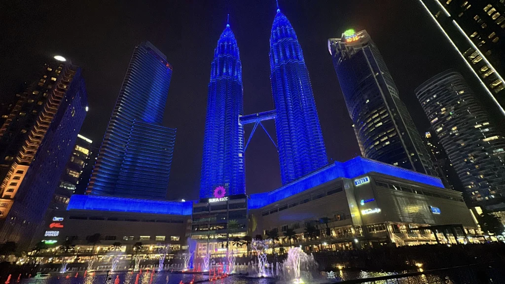 The Petronas Twin Towers lit blue above the KLCC fountains at night