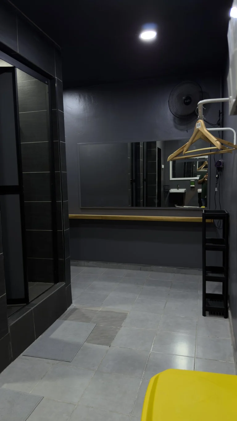 A dressing area in the shared bathroom at Travelogue Guesthouse, with a long mirror, a wooden ledge and a clothes hanger
