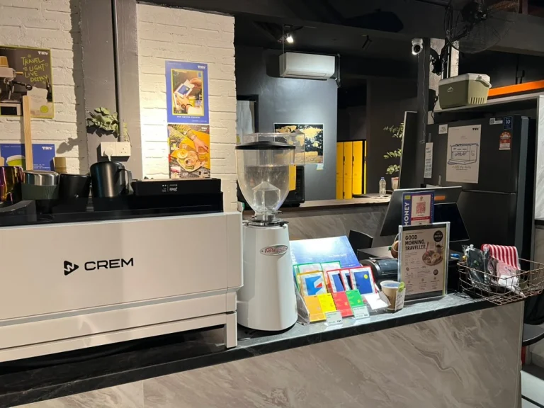 The coffee counter at Travelogue Guesthouse, with the espresso machine, a grinder and the menu on the bar