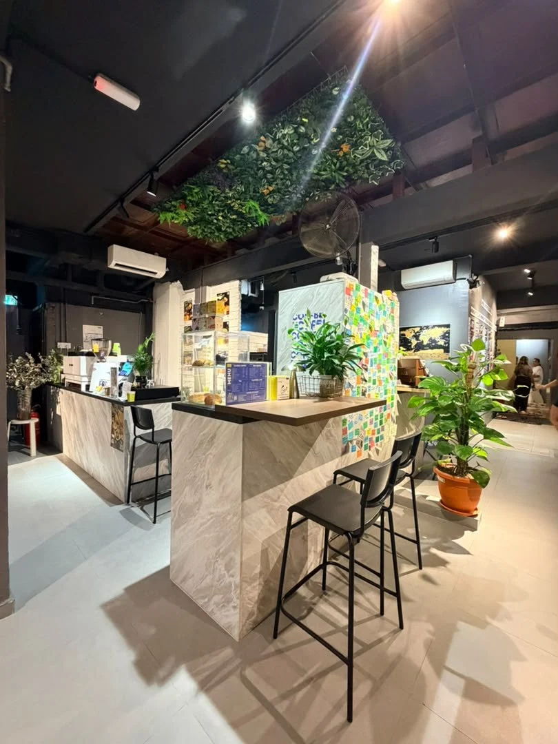 The marble coffee counter with bar stools and potted plants in the common area at Travelogue Guesthouse