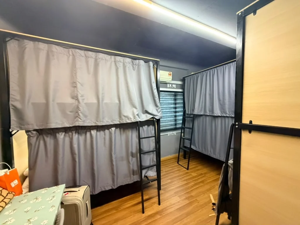 Metal-framed bunks with grey privacy curtains drawn, in a dormitory at Travelogue Guesthouse, Bukit Bintang