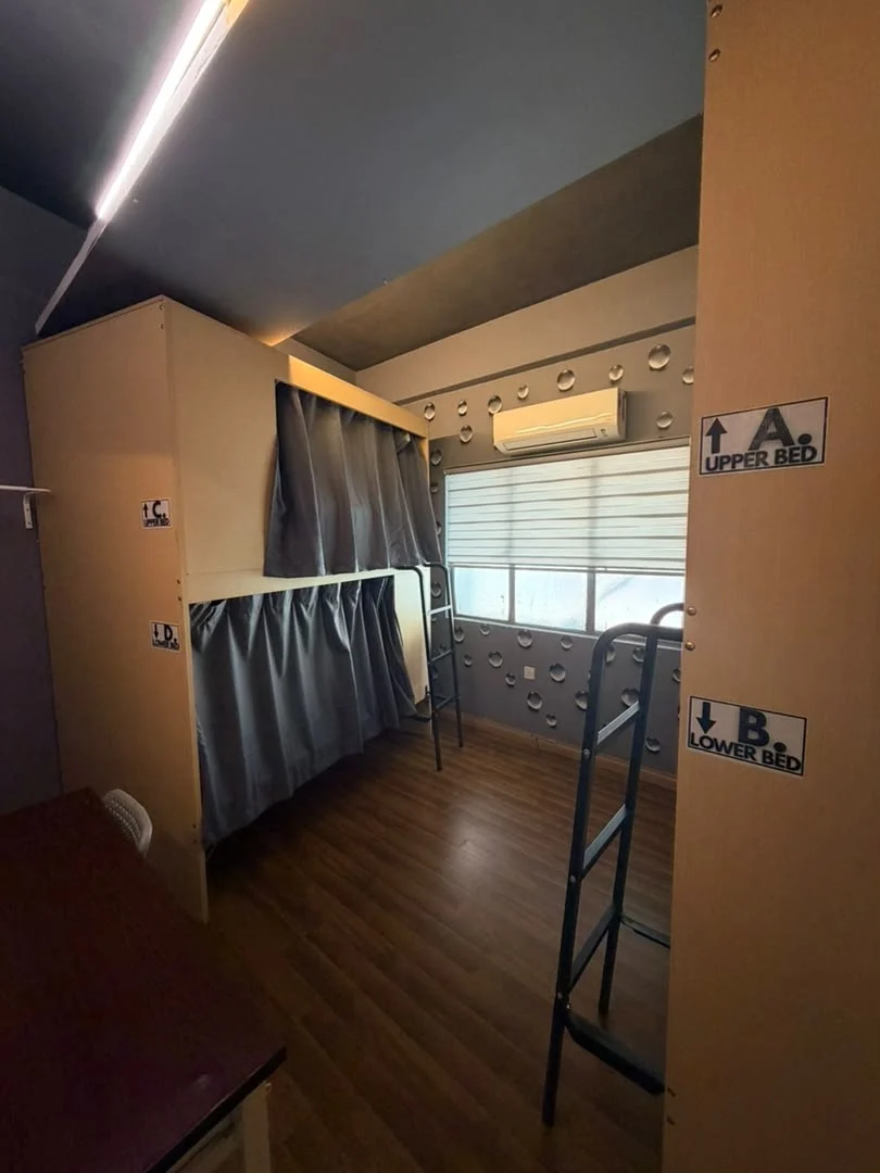 Bunks labelled upper bed and lower bed, with grey curtains, in a dormitory at Travelogue Guesthouse, Bukit Bintang