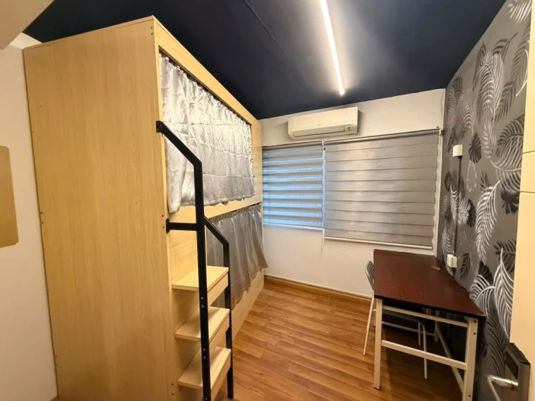 A wooden pod bunk, a desk and a patterned wall in a dormitory at Travelogue Guesthouse, Bukit Bintang