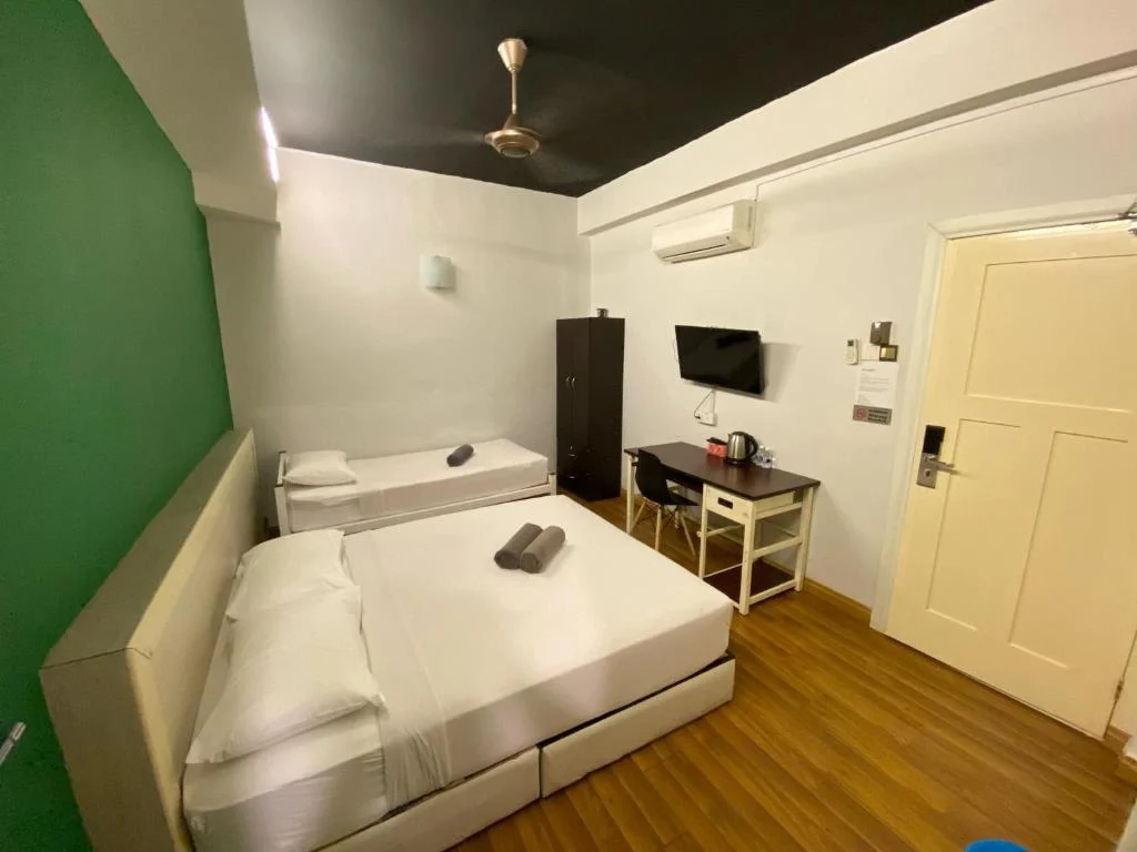 The desk, kettle and wall-mounted television in the family room at Travelogue Guesthouse, the beds beside them
