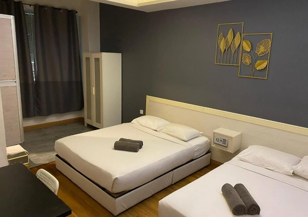 A double bed and a single bed made up with rolled towels in the family room at Travelogue Guesthouse, framed prints on the wall behind them