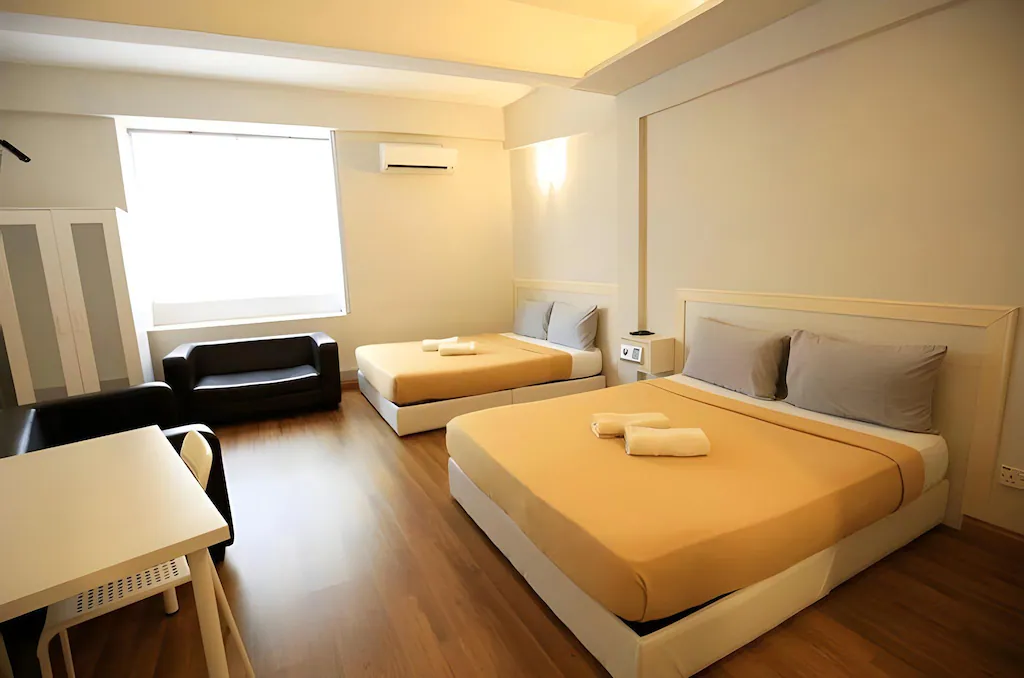 A Travelogue Guesthouse room with two beds made up with towels, a sofa, a desk and a window, Bukit Bintang