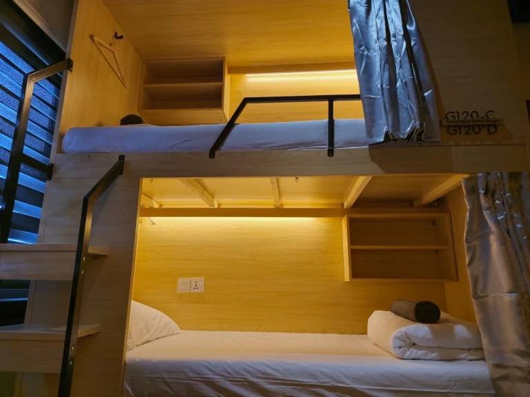 Inside a bunk in the female dormitory at Travelogue Guesthouse, with a reading light and a socket
