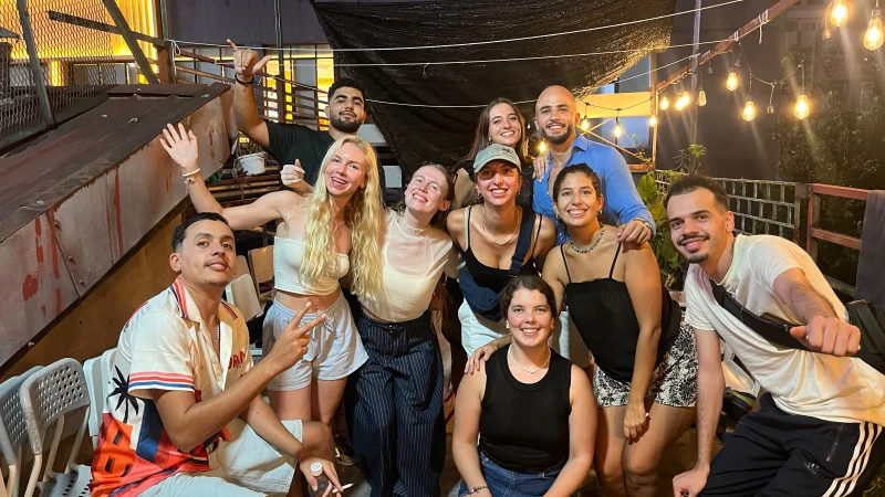 A large group of Travelogue Guesthouse guests together under string lights at night