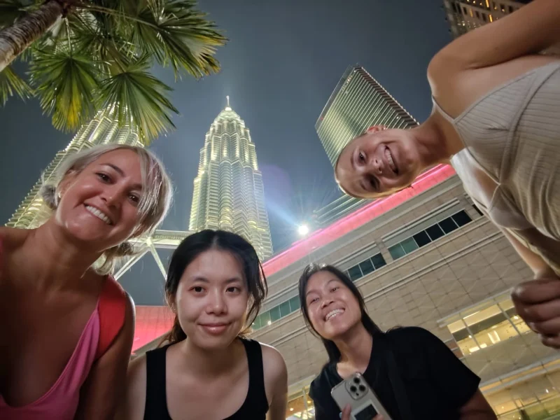 Travelogue Guesthouse guests below the Petronas Twin Towers in daylight