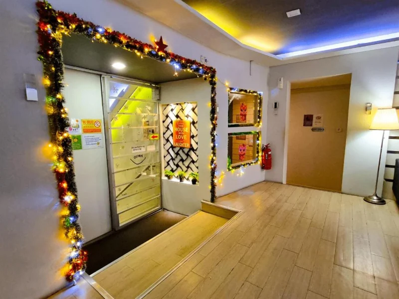 The top of the stairs at Travelogue Guesthouse, the glass door into reception ahead and fairy lights around the frame