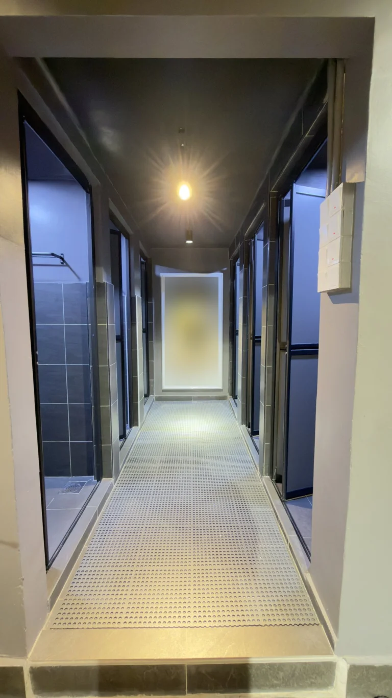 The corridor of shared shower and toilet cubicles at Travelogue Guesthouse, with doors along both sides