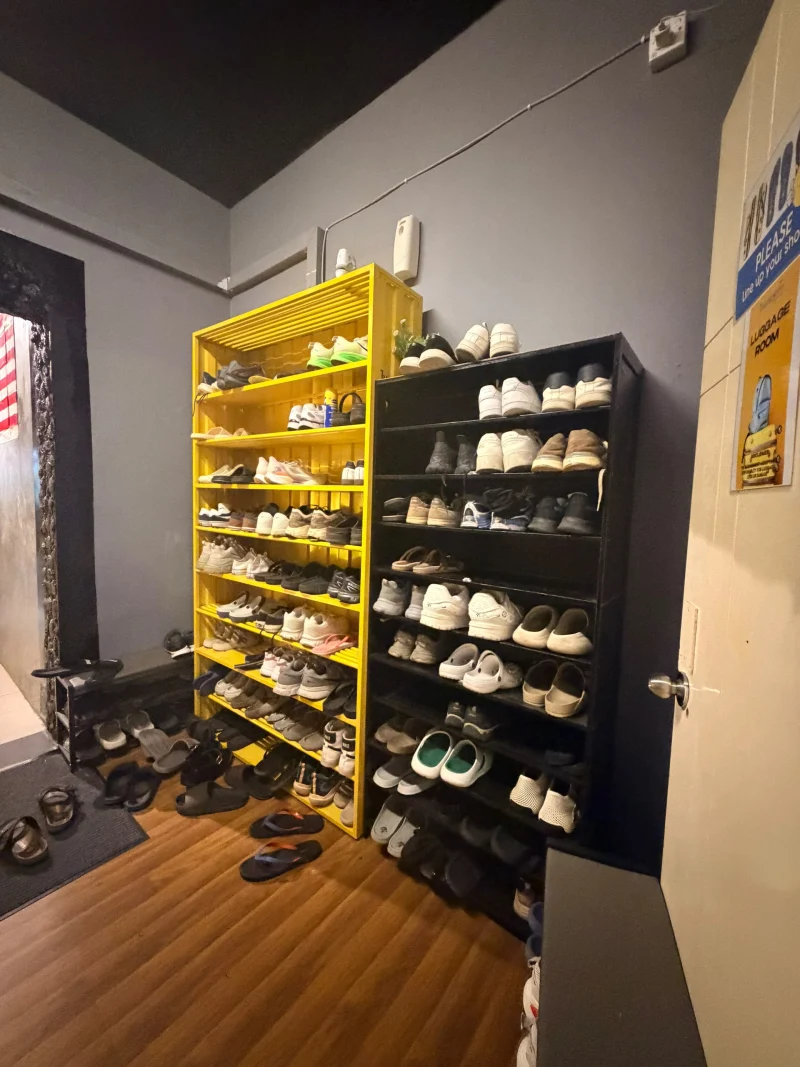 The shoe rack by the entrance at Travelogue Guesthouse, shoes left in yellow and black shelves