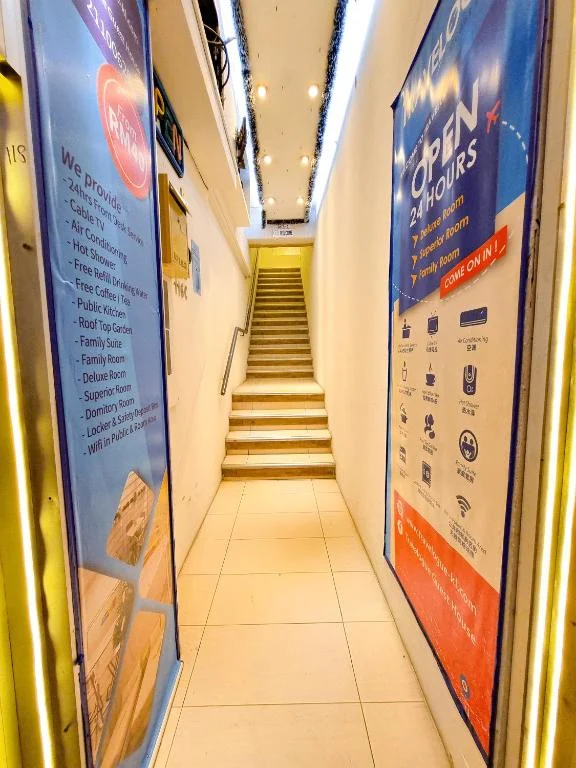 The corridor inside the Travelogue Guesthouse entrance and the staircase up to reception, posters along both walls