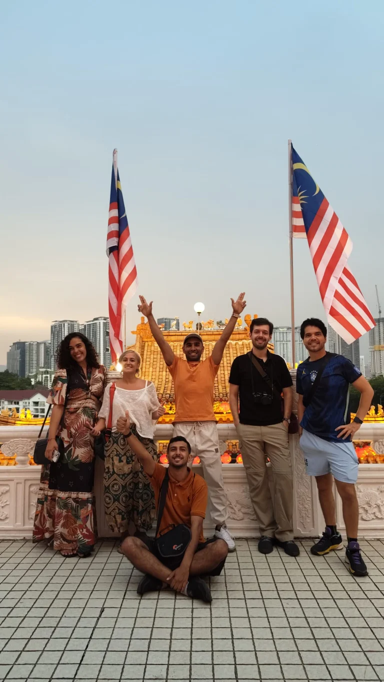 A Travelogue Guesthouse group below the flags at Thean Hou Temple at sunset