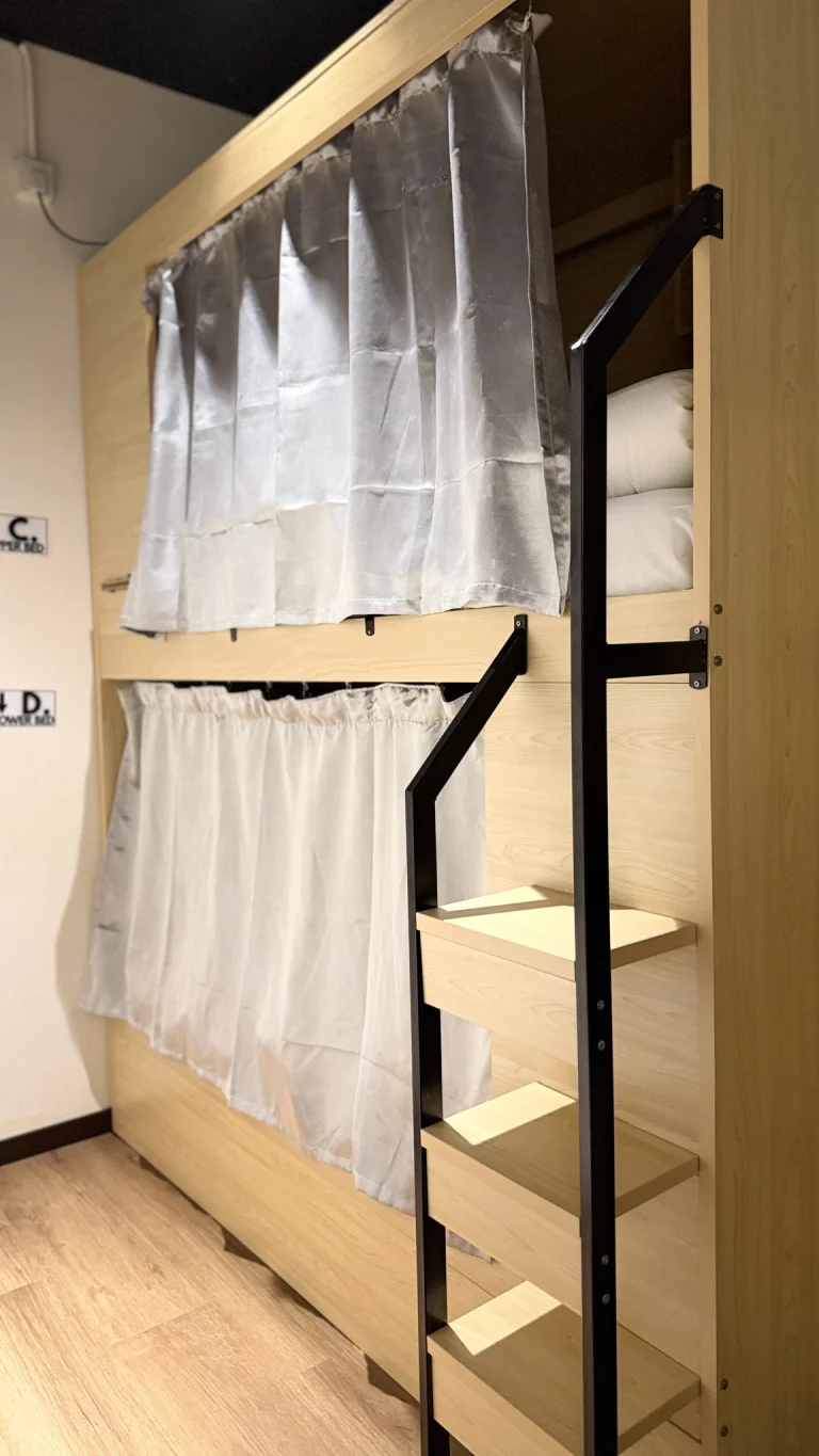 A pod bunk with curtains and a built-in ladder in the female dormitory at Travelogue Guesthouse